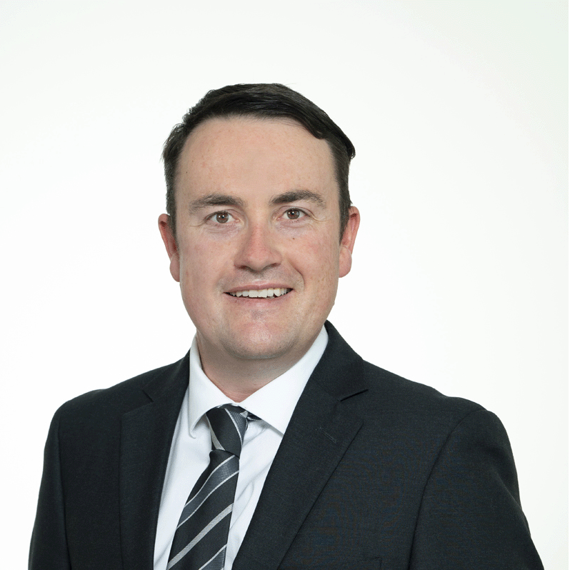 Headshot of Poultry Committee Chair Brendan Sharpe wearing a dark suit and striped tie, smiling against a light background.