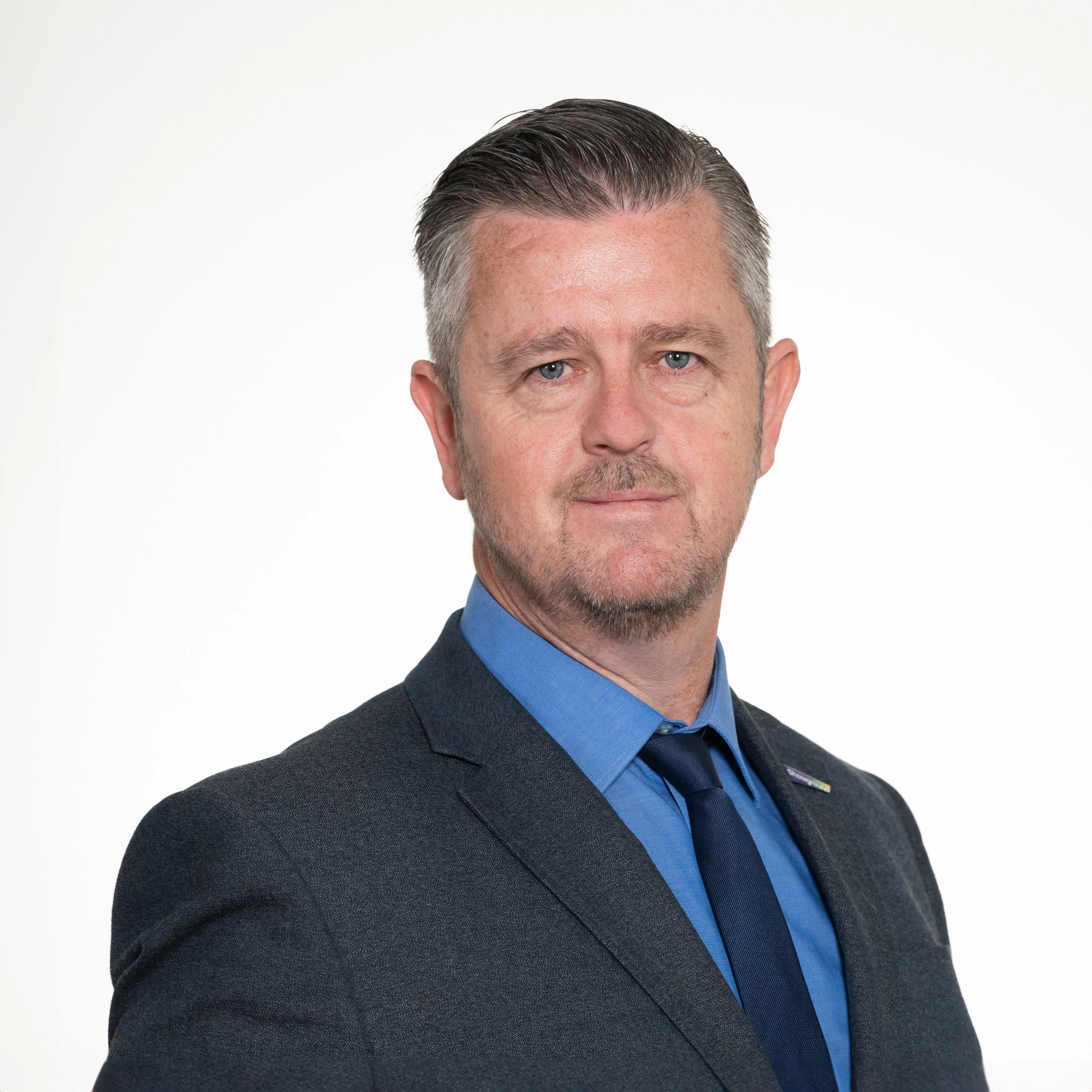 Headshot of Sydney Showground General Manager Darryl Jeffery, wearing a dark grey suit and blue shirt with a navy tie.