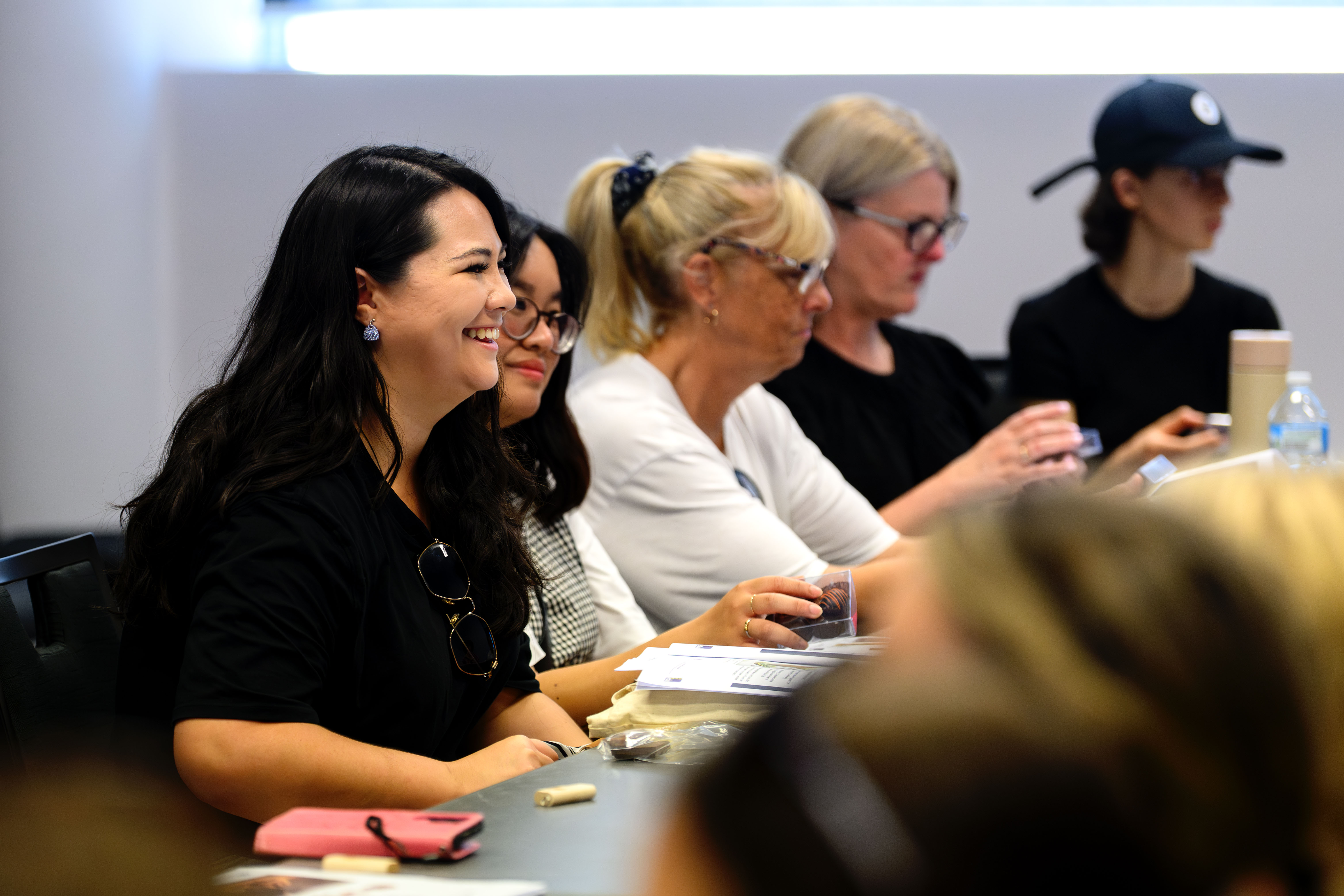 People seated in a classroom, smiling and engaging during a learning session.
