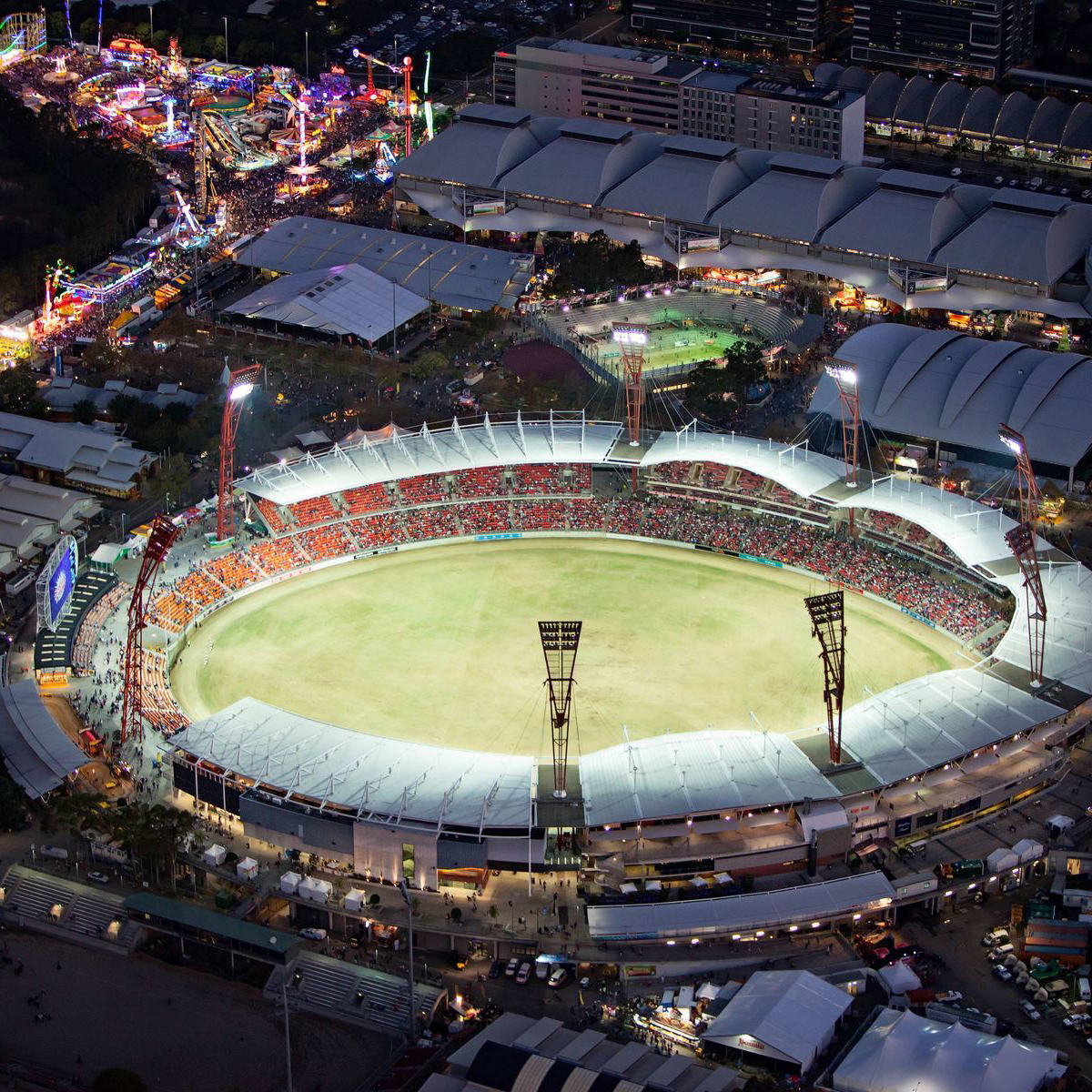 Aerial view of a brightly lit Sydney Showground, surrounded by bright lights and amusement rides at night.